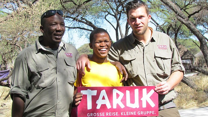 Reiseleiter mit San und Taruk Schild in Namibia