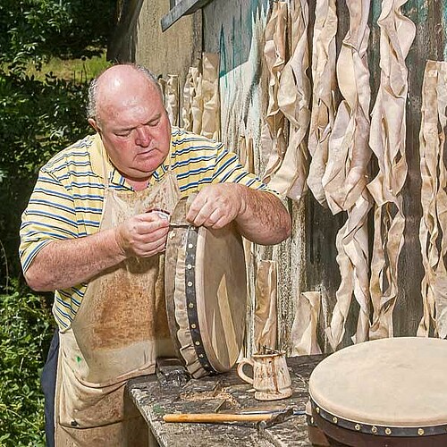 Mann bespannt traditionelle Trommel mit Fell in Irland.