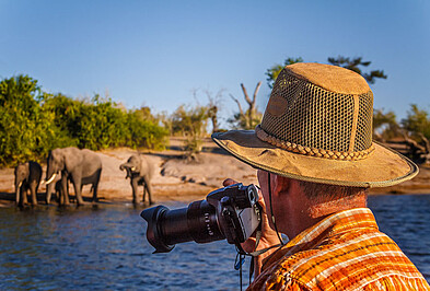 Mann mit Kamera fotografiert Elefanten im Caprivi Streifen in namibia
