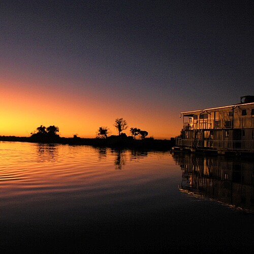 O Bona Okavango Houseboat bei Sonnenuntergang im Okavango Panhandle in Botswana