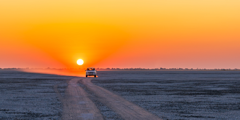 Fahrzeug vorm Sonnenuntergang über den Makgadikgadi Salzpfannen in Botswana