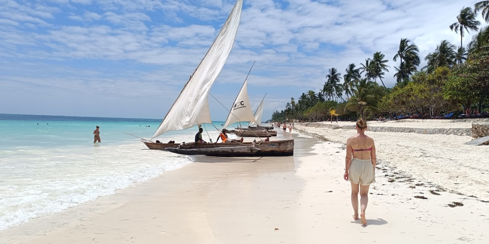 Frau und Dhow am Strand von Sansibar in Tansania